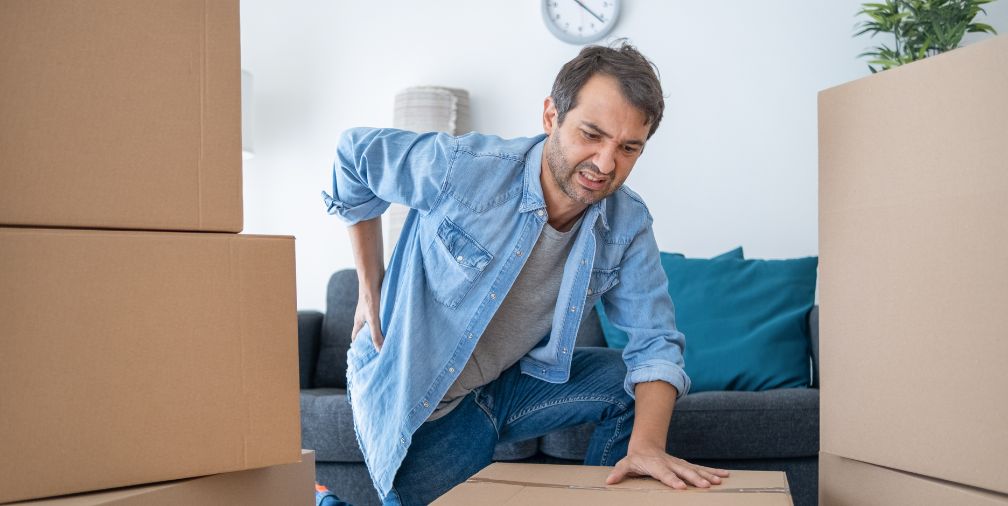 Man holding back kneeled down next to a box