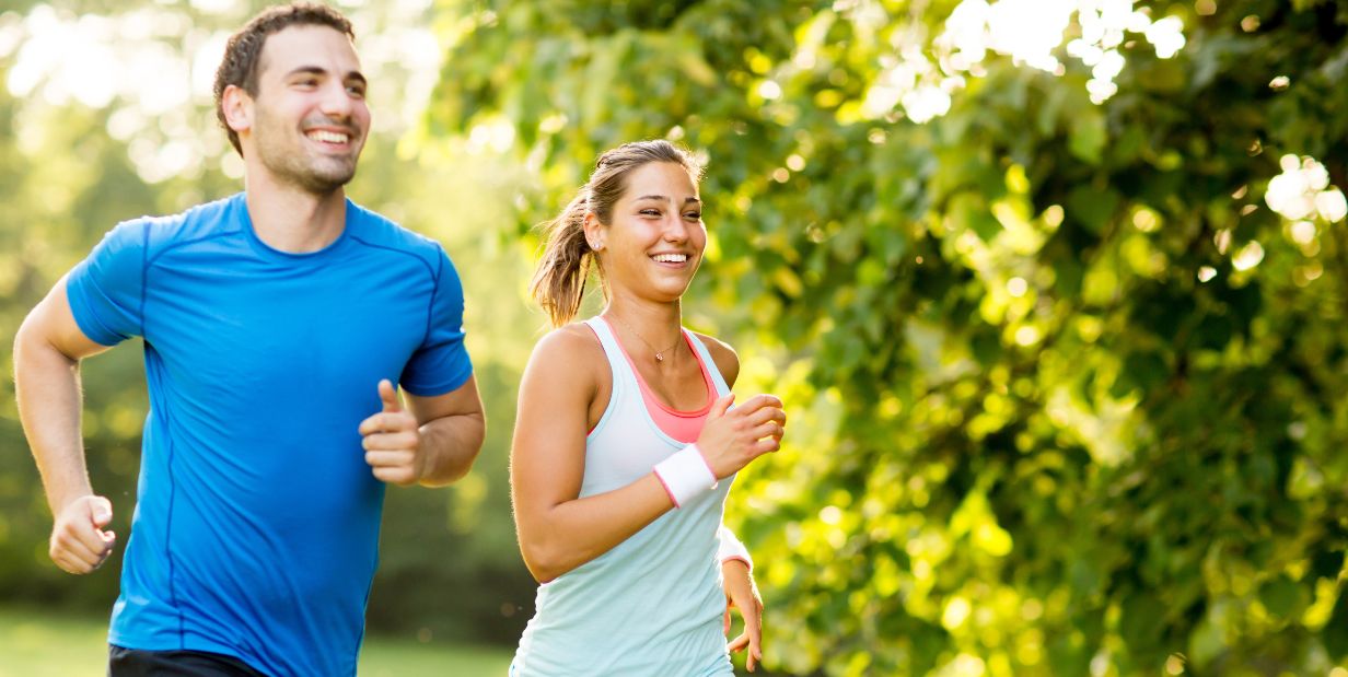 Man and woman running past trees 