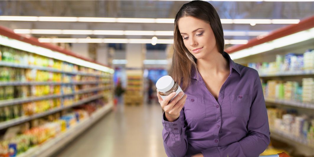 Woman looking at expiration date on jar in a grocery store