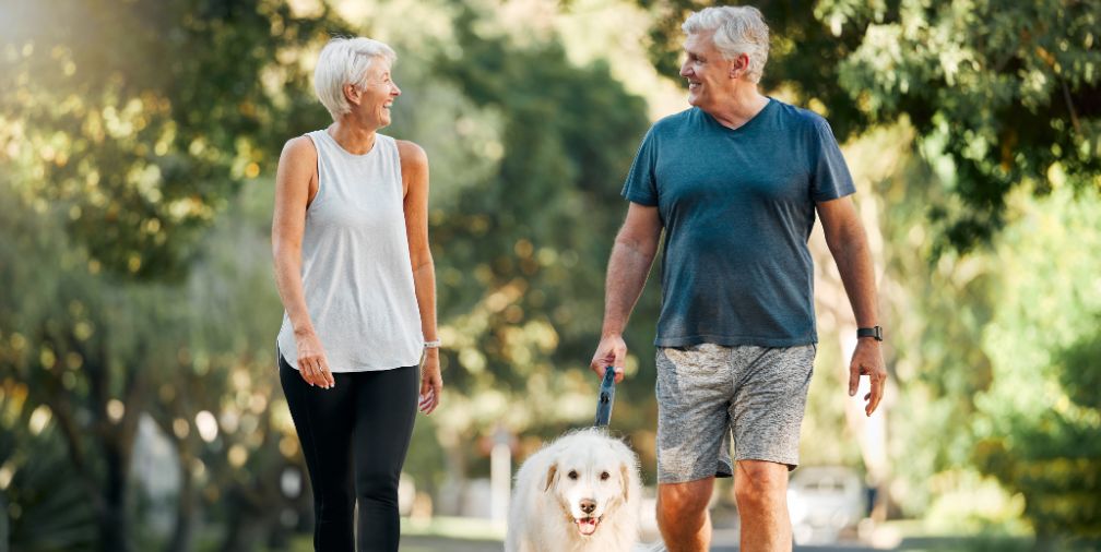 Older man and woman walking their dog