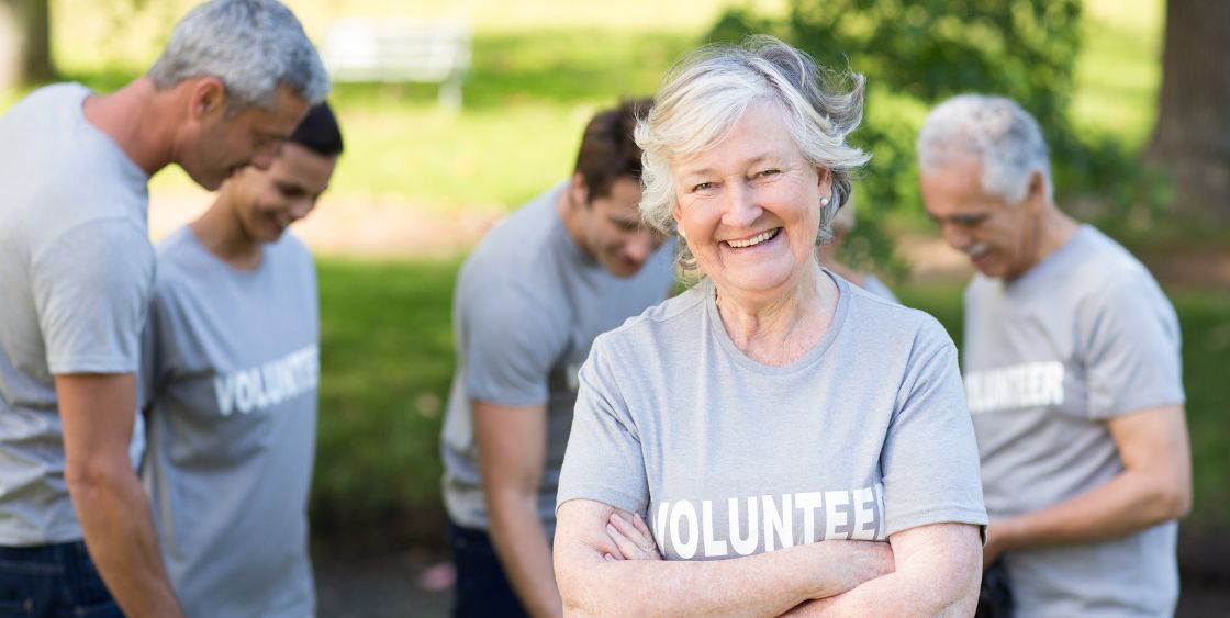 Older lady wearing volunteer shirt smiling 