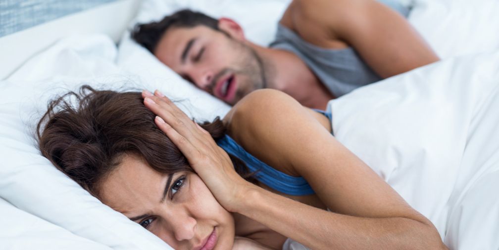 Woman covering her ears and Man snoring 