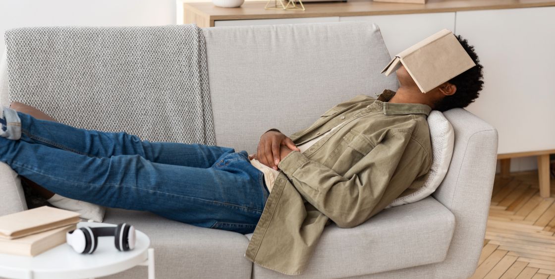 Man laying on the couch with book over his face