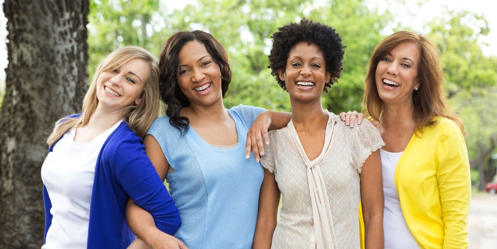 4 women smiling together outside