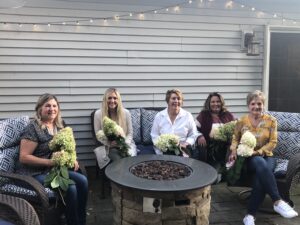 women holding flowers around a firepit