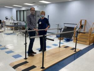 Dean Hauersperger and Jenny Long, Director of Rehabilitation Services and Physical Therapist, stand by the new parallel bars that were purchased with a recent donation from Mr. Hauersperger.